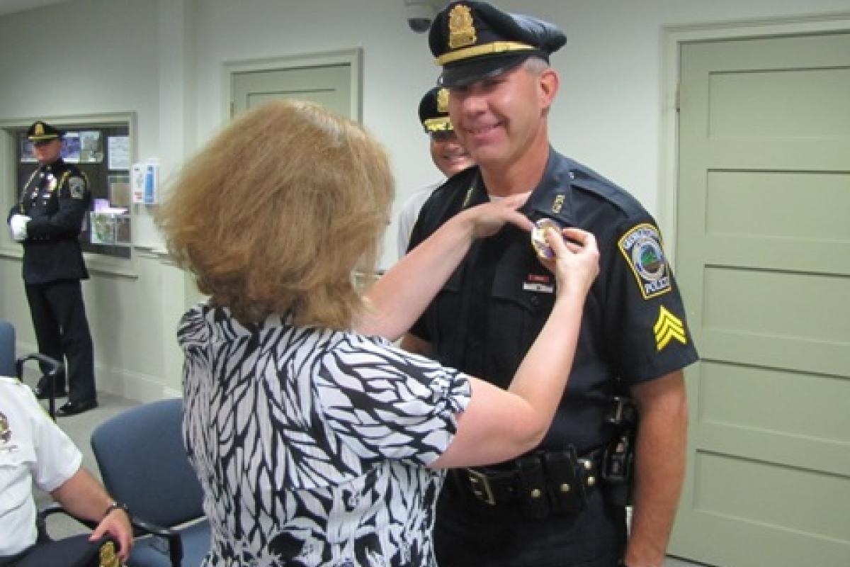 Officer Hatch has his new Sergeant's badge pinned to his uniform by his wife, Cathy.